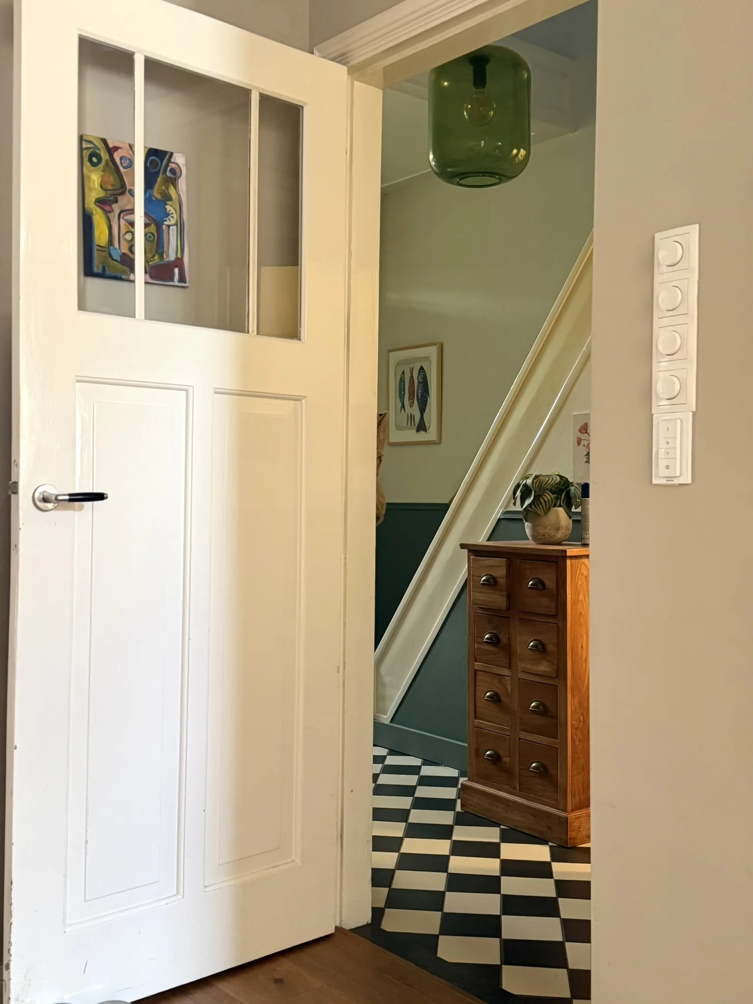 Doorkijk vanuit Pleunies woonkamer naar de hal met kunst, groen glas en een grafische tegelvloer