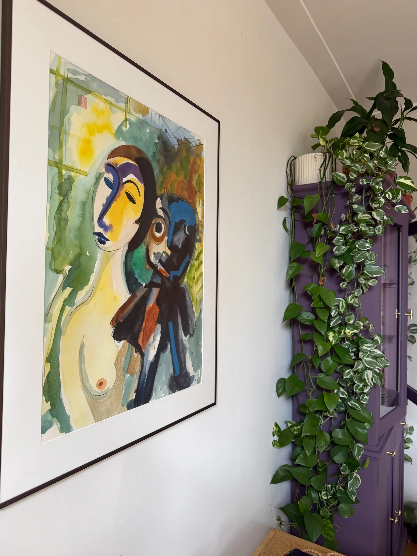 Woonkamer decoratie met kunst, een gekleurde kast, boeken en groene planten