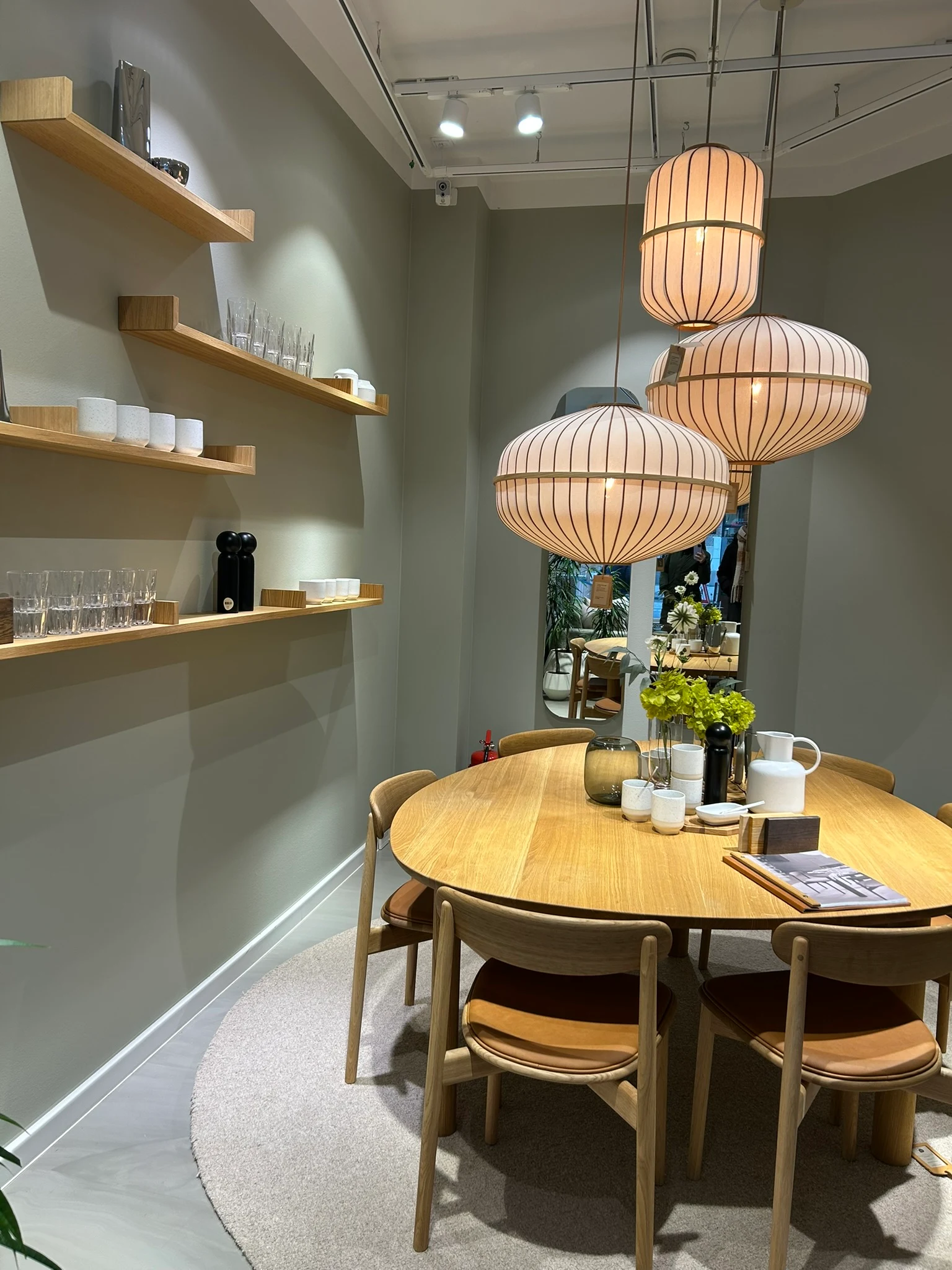 Sfeeropstelling met houten eettafel, groene wand en zacht verlichte hanglampen